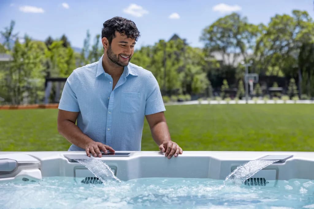 Man standing at a Bullfrog A-Series hot tub with two waterfall features running