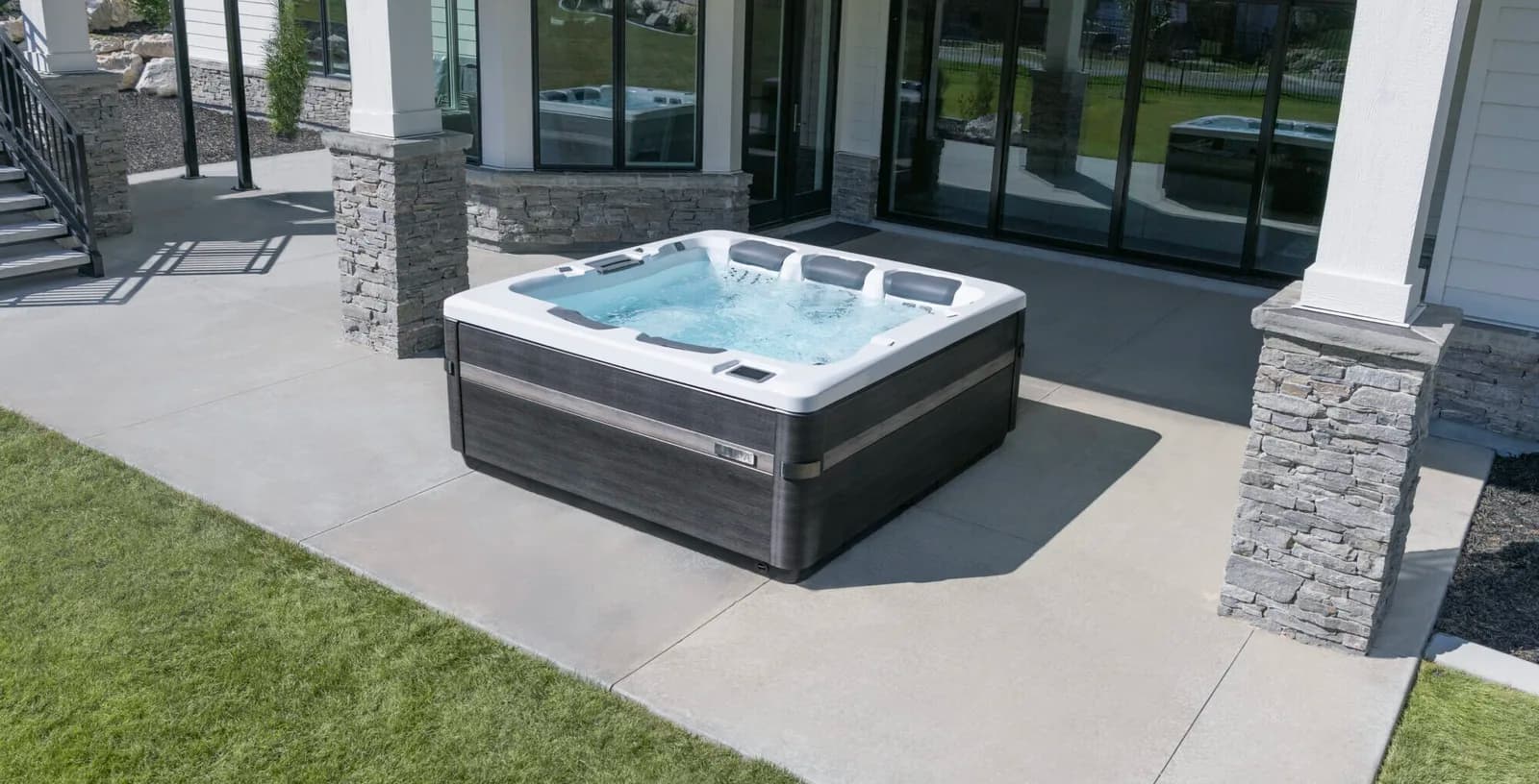 Bullfrog A-Series hot tub installed on a concrete patio beside a modern home