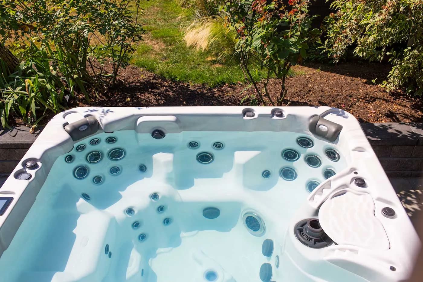 Close-up of a Clearwater Spas acrylic shell showing contoured seats and jets in a garden setting