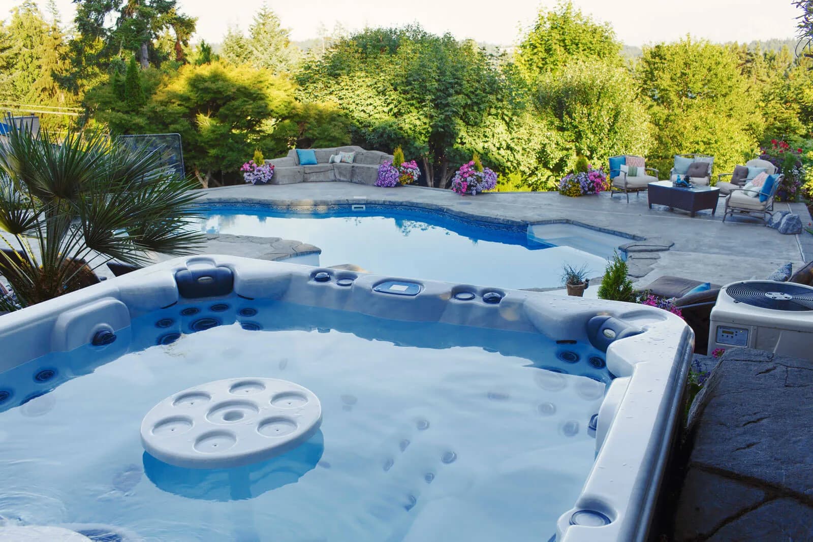 Clearwater Spas hot tub with a round center drink table, set beside an in-ground pool in a landscaped backyard