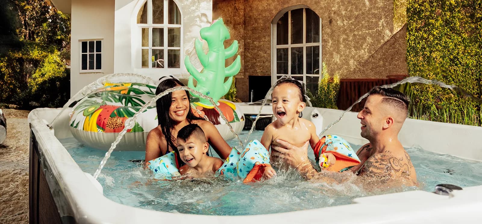 Family playing in a Coast Spas swim spa with water jets and pool floats