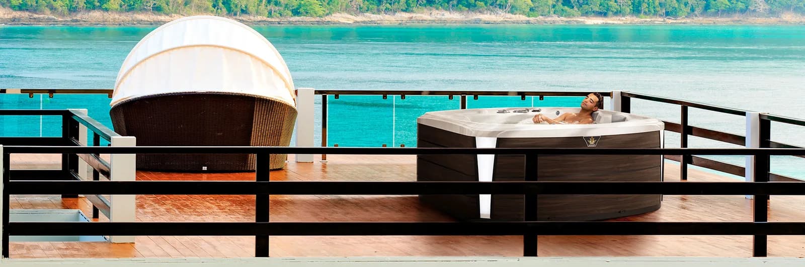 Man relaxing in a Marquis Crown Resort hot tub on a waterfront deck