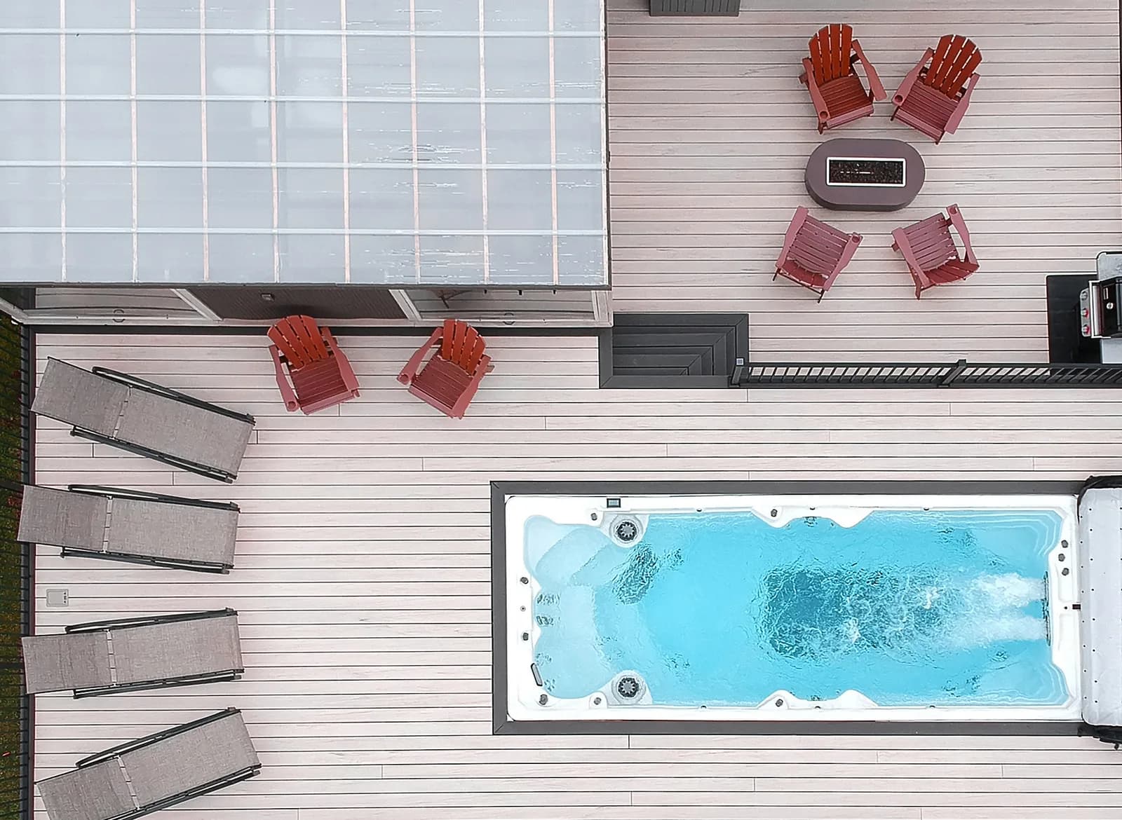 PDC Spas swim spa set into a deck with patio loungers and a dining area